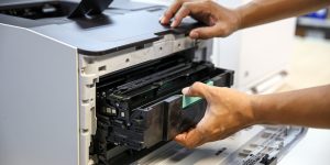Technician hand open cover printer photocopier or photocopy to replace ink cartridges or fix paper jam for scanning fax or copy document in office workplace.